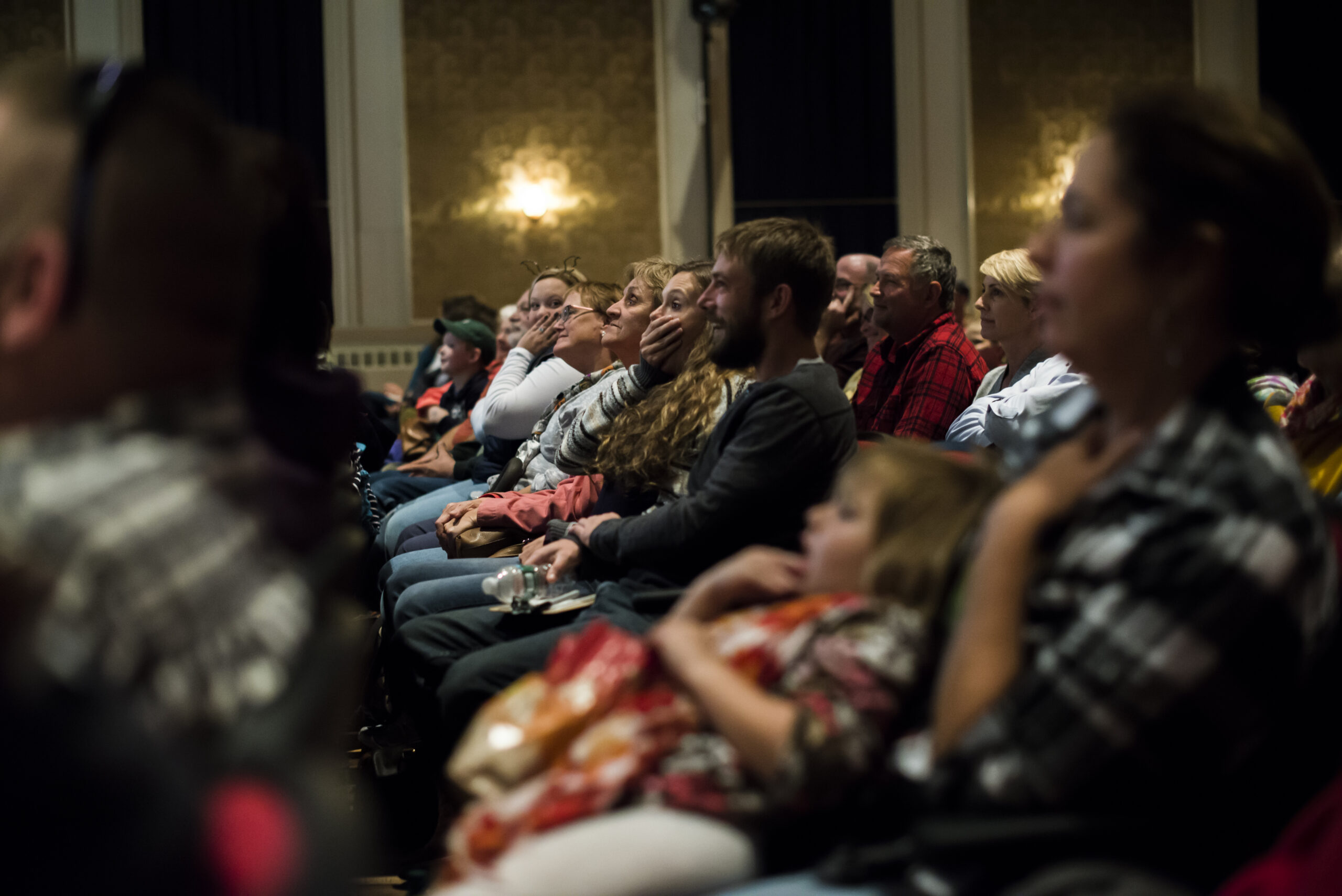 Audience members with hands over their mouths in disbelief