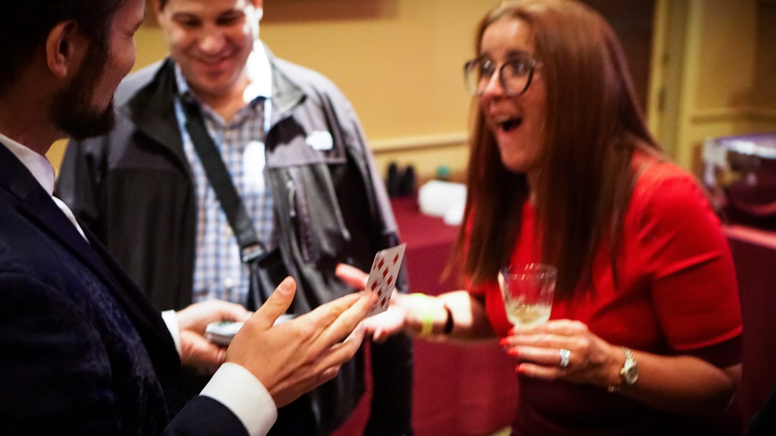 A guest reacting with astonishment to a card revelation at a corporate holiday party